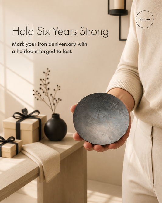 A person holding a metal anniversary dish in one hand. A table with presents in it inthe background.