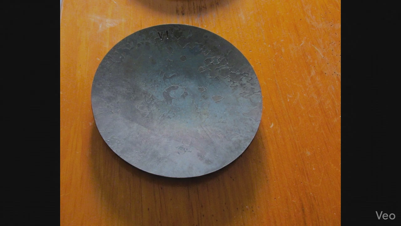 a woman picks up a steel anniversary dish  as she touches and admires the rustic steel finish.