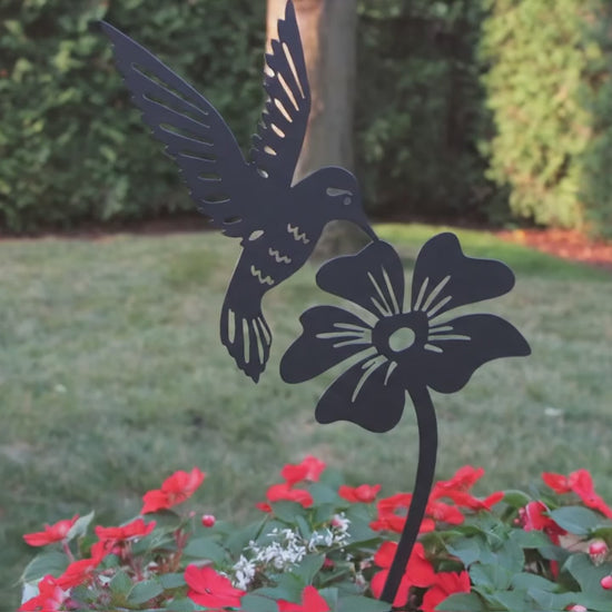 A close up view of a  hummimgbird and flower garden stake in a flower pot.