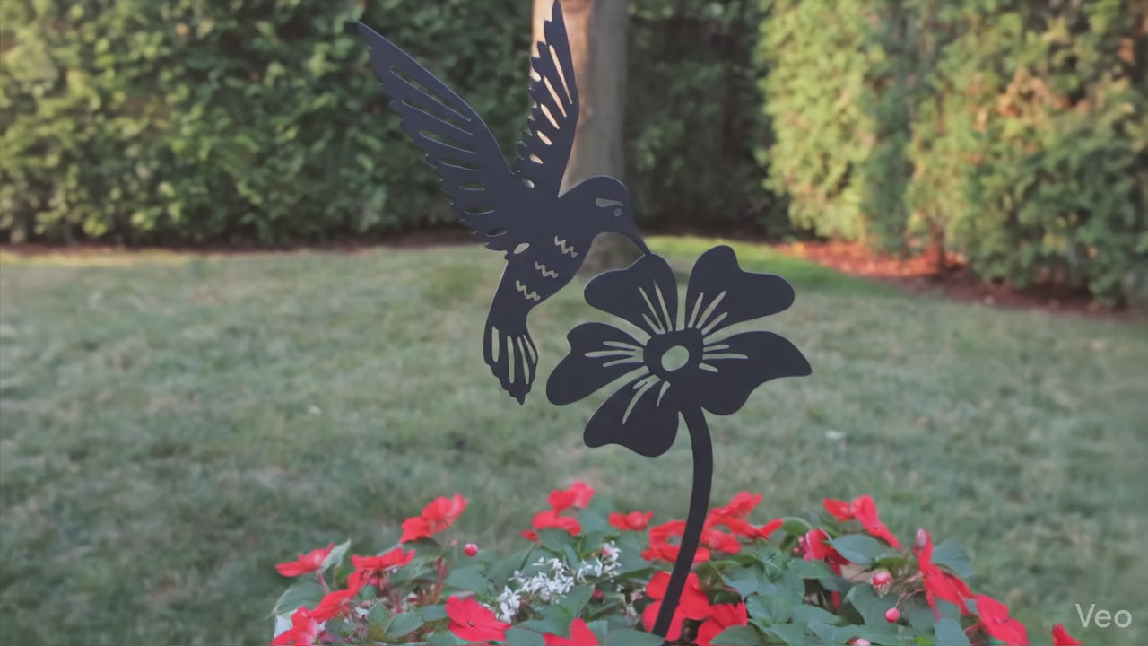 A close up view of a  hummimgbird and flower garden stake in a flower pot.